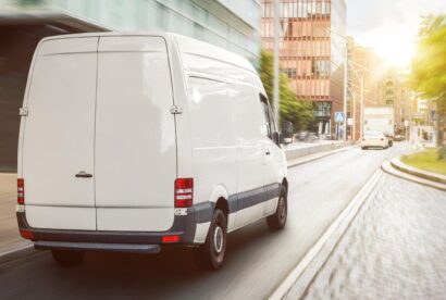 A fast white delivery van in motion with motion blur emphasizing speed.