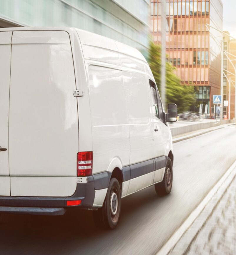 A fast white delivery van in motion with motion blur emphasizing speed.