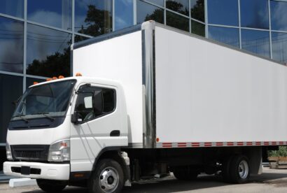 A large commercial moving truck parked in front of a modern corporate office building.