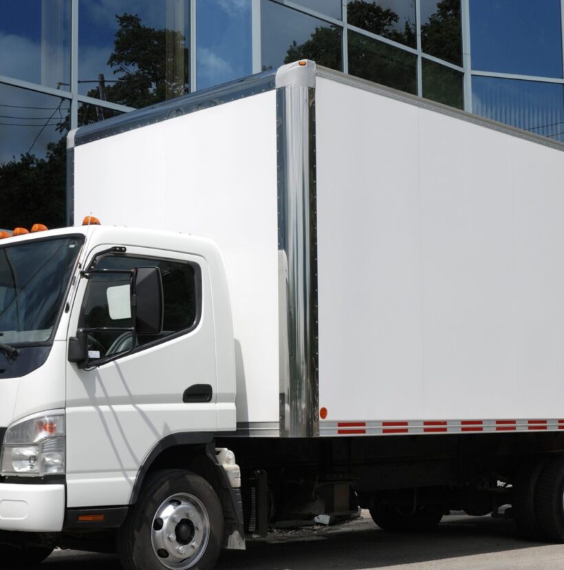 A large commercial moving truck parked in front of a modern corporate office building.